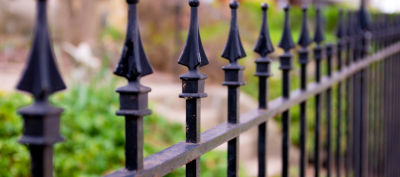 Traditional metal park railings with areas of rust on the surface 